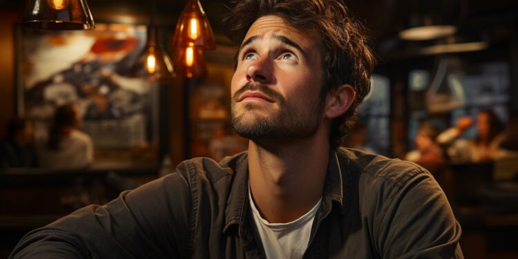 Young bearded man gazing upward in warmly lit bar