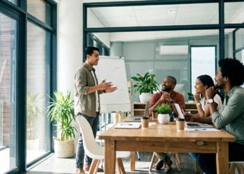 A leader telling a story to engaged colleagues in a bright modern meeting room