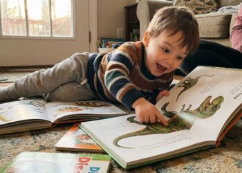 A child excitedly reading dinosaur picture books at home