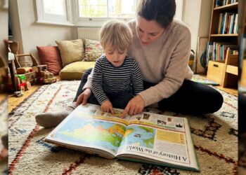Parent and child reading an illustrated history book together on a rug