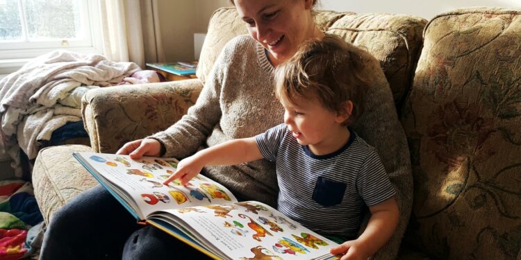 Parent and young child reading a colorful question-and-answer book together on a couch