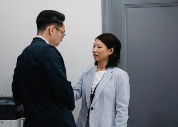 Two colleagues having a candid conversation in an office hallway