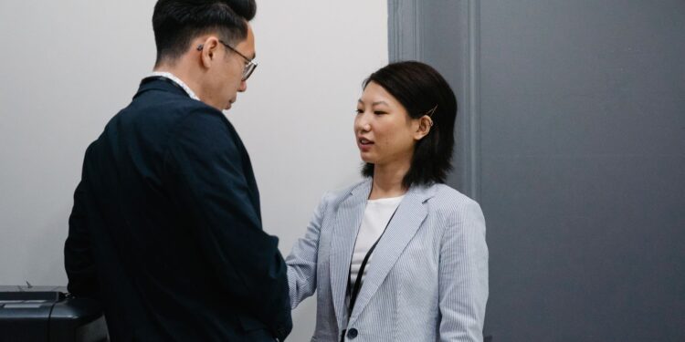 Two colleagues having a candid conversation in an office hallway